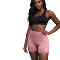 Woman wearing a black sports bra and pink shorts on a white background