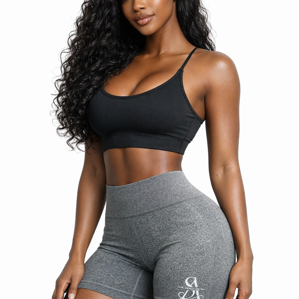 Woman wearing a black sports bra and gray shorts on a white background